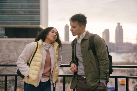Two people leaning on a railing while chatting.